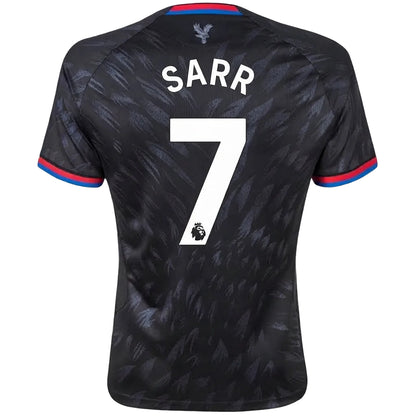 Back view of a Tottenham Hotspur football jersey with 'SARR' and the number 7 printed in white, featuring a dark patterned design with red and blue trim on the collar and sleeve cuffs.