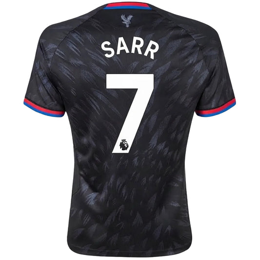 Back view of a Tottenham Hotspur football jersey with 'SARR' and the number 7 printed in white, featuring a dark patterned design with red and blue trim on the collar and sleeve cuffs.