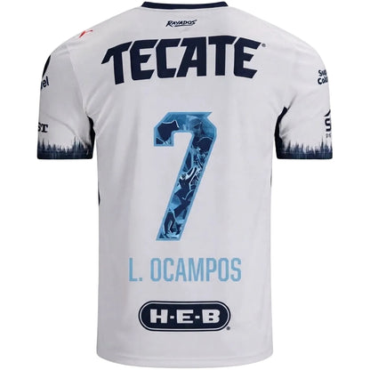 White short-sleeve soccer jersey shown from the back, featuring large navy 'TECATE' lettering, a blue patterned number 7, 'L. OCAMPOS' in light blue, and an H-E-B sponsor logo near the bottom.